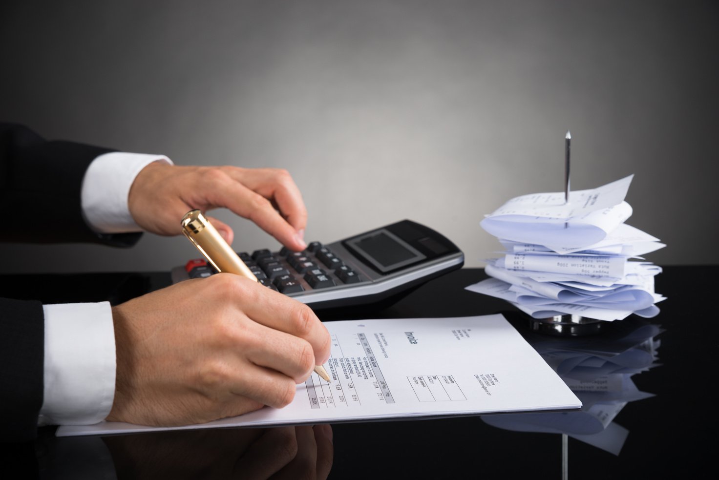 Businessperson Calculating Invoice At Desk